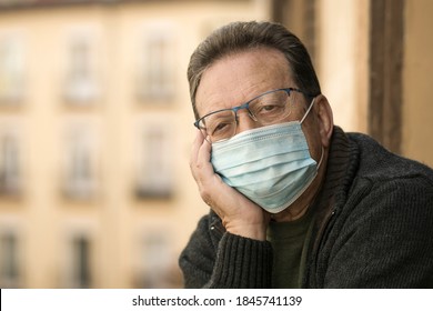 mature man in balcony home lockdown during covid19 outbreak - senior male on his 70s in face mask worried and tired looking to the street thoughtful and depressed in quarantine - Powered by Shutterstock