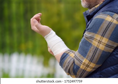 Mature man bandaging up his arm elastic bandage. Sprain ligaments wrist. Sports and domestic injuries. Health insurance. Sick leave. - Powered by Shutterstock