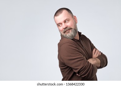 Mature Man With Beard In Brown T-shirt Looking Back Over His Shoulder In Studio. What Did You Ask Concept.