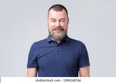 Mature Man In Blue Shirt Wrinkled Due To Sour Taste. Grimacing From The Unpleasant Sensation Or Sound