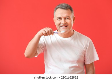 Mature Man Brushing Teeth On Color Background