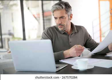 Mature man calculating budget on laptop