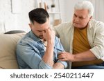 Mature man calming his upset son at home