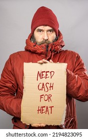 Mature Man With Cardboard Sign With Need Cash For Heat Text  In Thick Winter Coat At Freezing Cold Temperatures