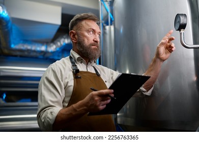 Mature man checking gauge valve indicator at brewery plant - Powered by Shutterstock