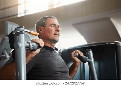 Mature man, chest press and workout with machine for fitness, training or indoor exercise at gym. Active male person with earphones on equipment for strength, muscle gain or wellness at health club - Powered by Shutterstock