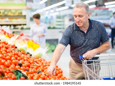 Mature man considering tomatoes in vegetables section of supermarket  - Powered by Shutterstock