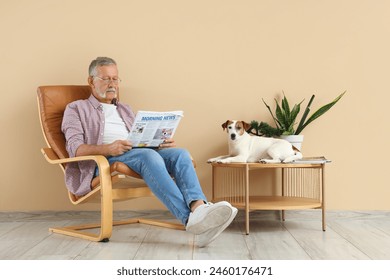 Mature man with cute Jack Russell terrier reading newspaper in armchair at home - Powered by Shutterstock