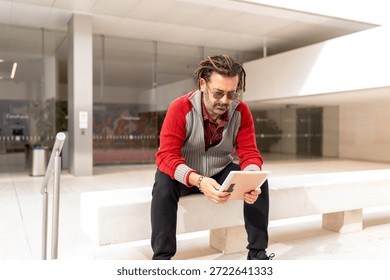 Mature Man with Dreadlocks Using Digital Tablet on City Bench