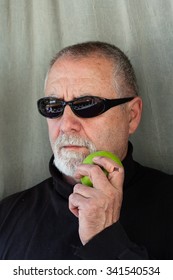 Mature Man Dressed In Black Eating An Apple