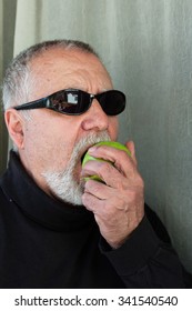 Mature Man Dressed In Black Eating An Apple