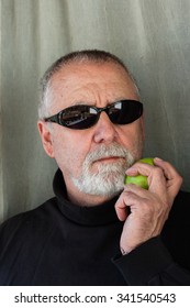 Mature Man Dressed In Black Eating An Apple