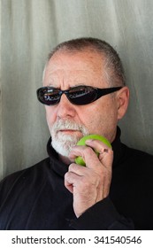 Mature Man Dressed In Black Eating An Apple