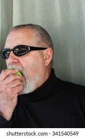 Mature Man Dressed In Black Eating An Apple