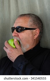 Mature Man Dressed In Black Eating An Apple