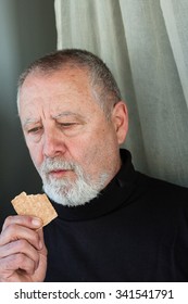 Mature Man Dressed In Black Eating A Cracker