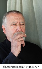 Mature Man Dressed In Black Eating A Cracker