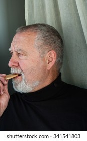 Mature Man Dressed In Black Eating A Cracker