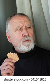 Mature Man Dressed In Black Eating A Cracker