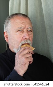 Mature Man Dressed In Black Eating A Cracker