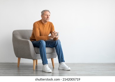 Mature man drinking coffee sitting on chair in living room. Casual adult guy relaxing, enjoying weekend free time, mockup free copy space, full body length, isolated on white studio background wall - Powered by Shutterstock