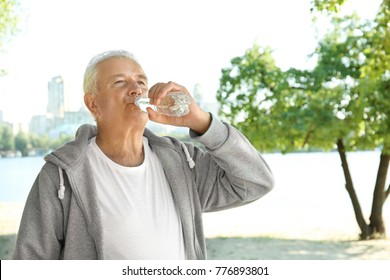 Mature man drinking water on beach - Powered by Shutterstock