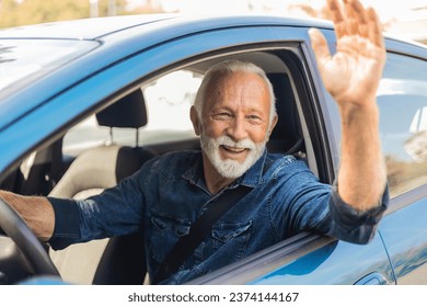 Mature man driving car and waving. Close up portrait of senior business man sitting in the car and laughing while waving. - Powered by Shutterstock