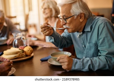 Mature Man Eating Soup While Having Lunch At Residential Care Home 