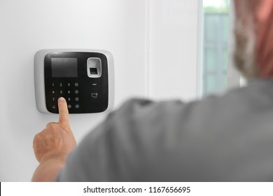 Mature Man Entering Code On Alarm System Keypad Indoors