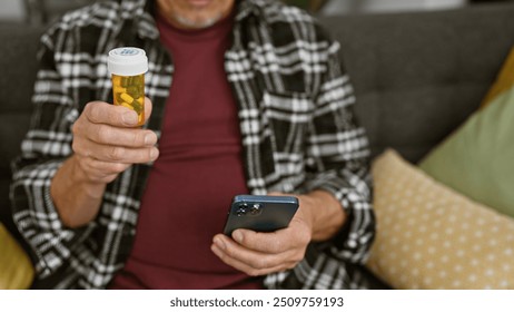 Mature man examining medication bottle while using smartphone at home, embodying health management and domestic life. - Powered by Shutterstock