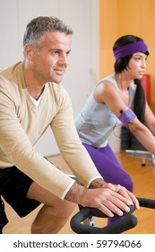 Mature Man Exercising With Bicycle At Gym