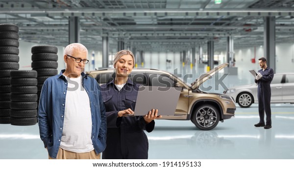 Mature man and a female auto\
mechanic looking at a laptop computer in a auto repair workshop\
