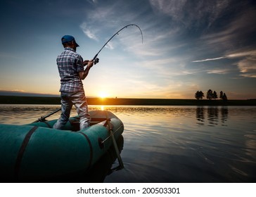 Mature man fishing from the boat on the pond at sunset - Powered by Shutterstock