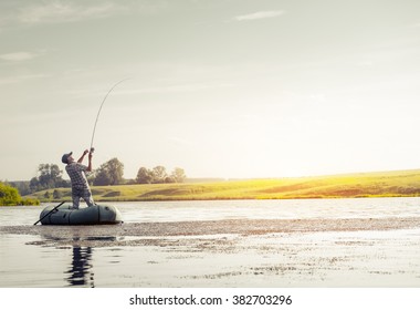 Mature Man Fishing On The Lake From Inflatable Boat