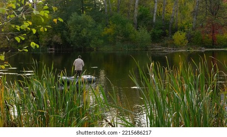 Mature Man Fishing On The River From Inflatable Boat,