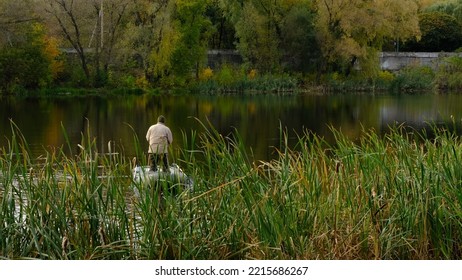 Mature Man Fishing On The River From Inflatable Boat,