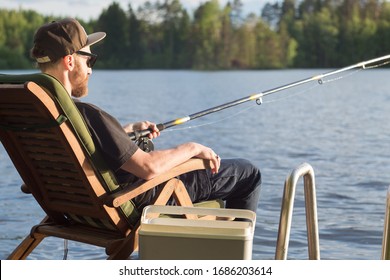 Reifender Mensch, der im Sommer von Holzsteg in der Nähe von Hütte am See in Finnland fischen