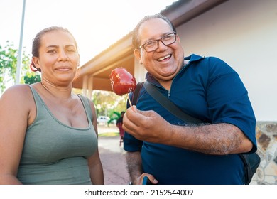 Mature Man Flirting With A Green-eyed Woman With A Caramel Apple In A Park In The City Of Managua.