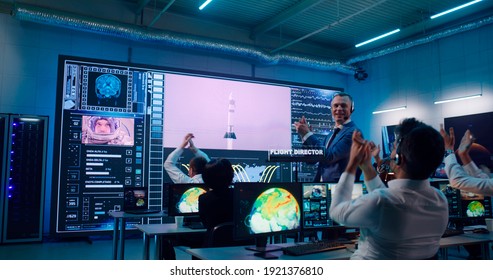 Mature Man Giving High Fives And Kissing Applauding Colleagues After Successful Rocket Launch In Flight Control Center