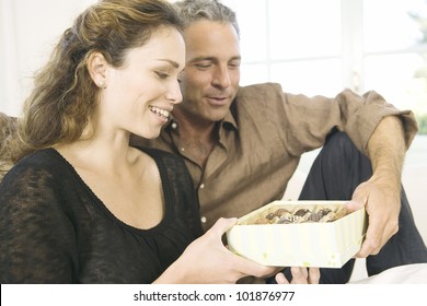 Mature Man Giving  A Woman A Box Of Chocolates At Home.