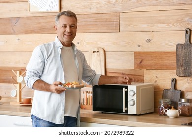 Mature Man Heating Food In Microwave Oven