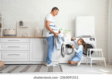 Mature man with his little granddaughter doing laundry at home - Powered by Shutterstock