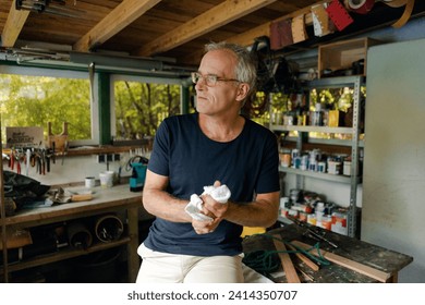 Mature man in his workshop cleaning his hands - Powered by Shutterstock