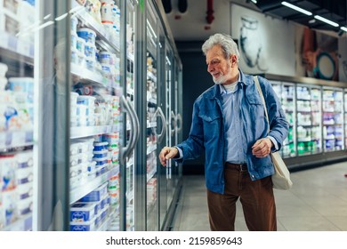 Mature Man Holding Canvas Bag On His Shoulder And Looking For Products In The Frozen Goods Section.