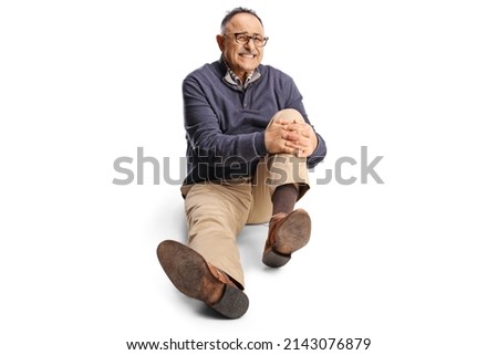 Mature man in holding his painful knee and sitting on the ground isolated on white background