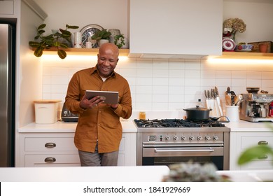 Mature Man At Home In Kitchen Looking At Digital Tablet - Powered by Shutterstock