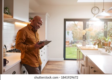 Mature Man At Home In Kitchen Looking At Digital Tablet - Powered by Shutterstock