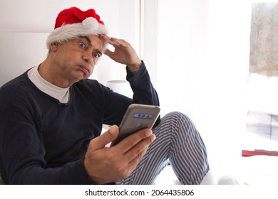 mature man huffing puffing with santa hat and mobile phone. hating christmas