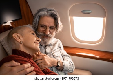 Mature Man Hugging Smiling Wife In Private Jet