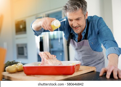 Mature Man In Kitchen Cooking Dish For Dinner